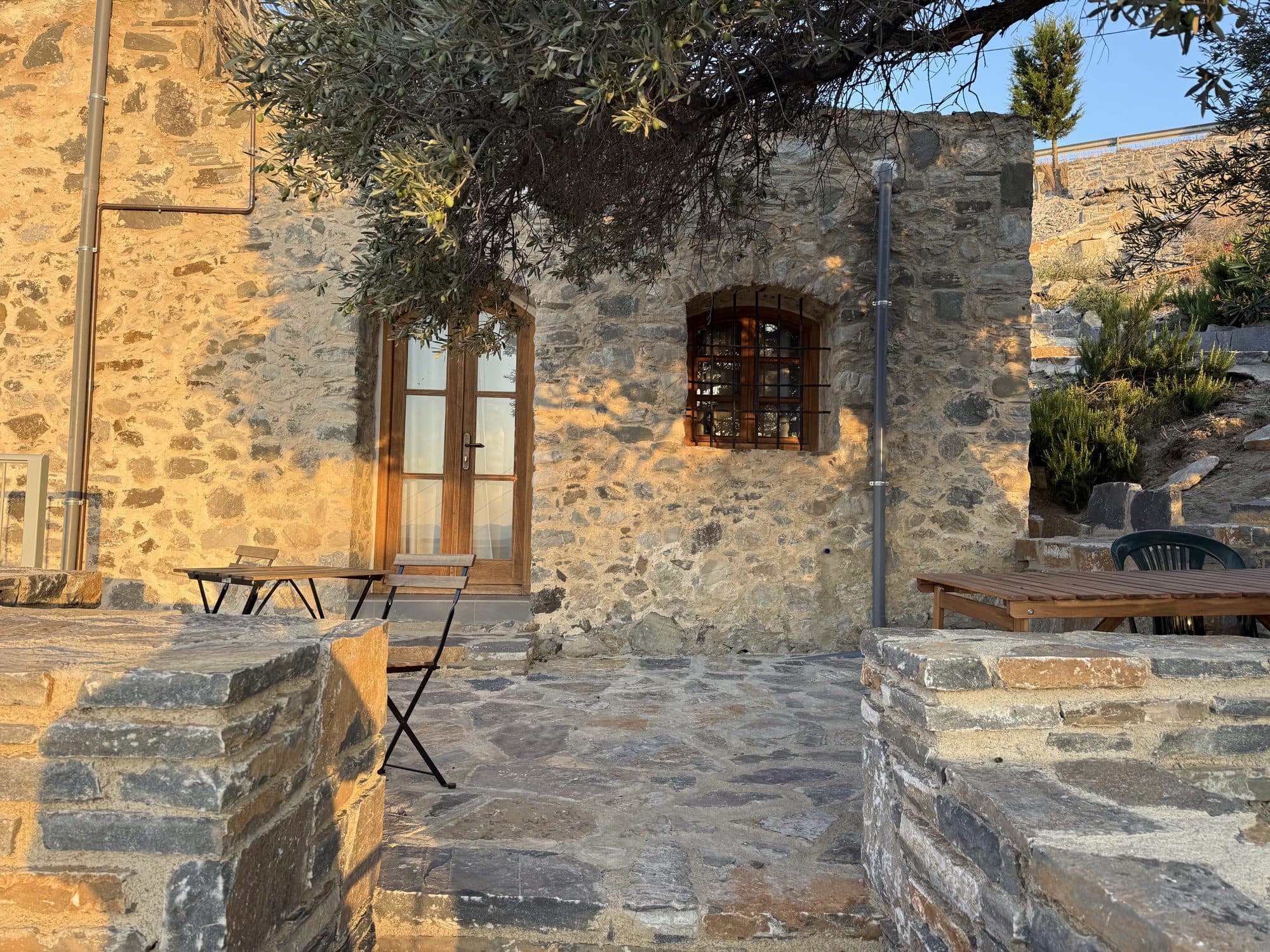 The stone house and shaded terrace in the morning sun