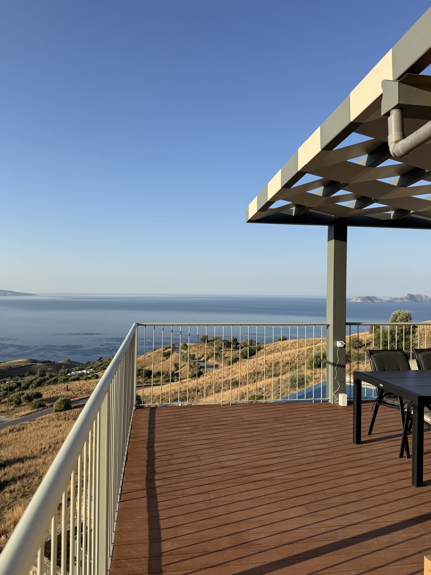 Terrace dining table under the sun umbrella, sea and hills beyond