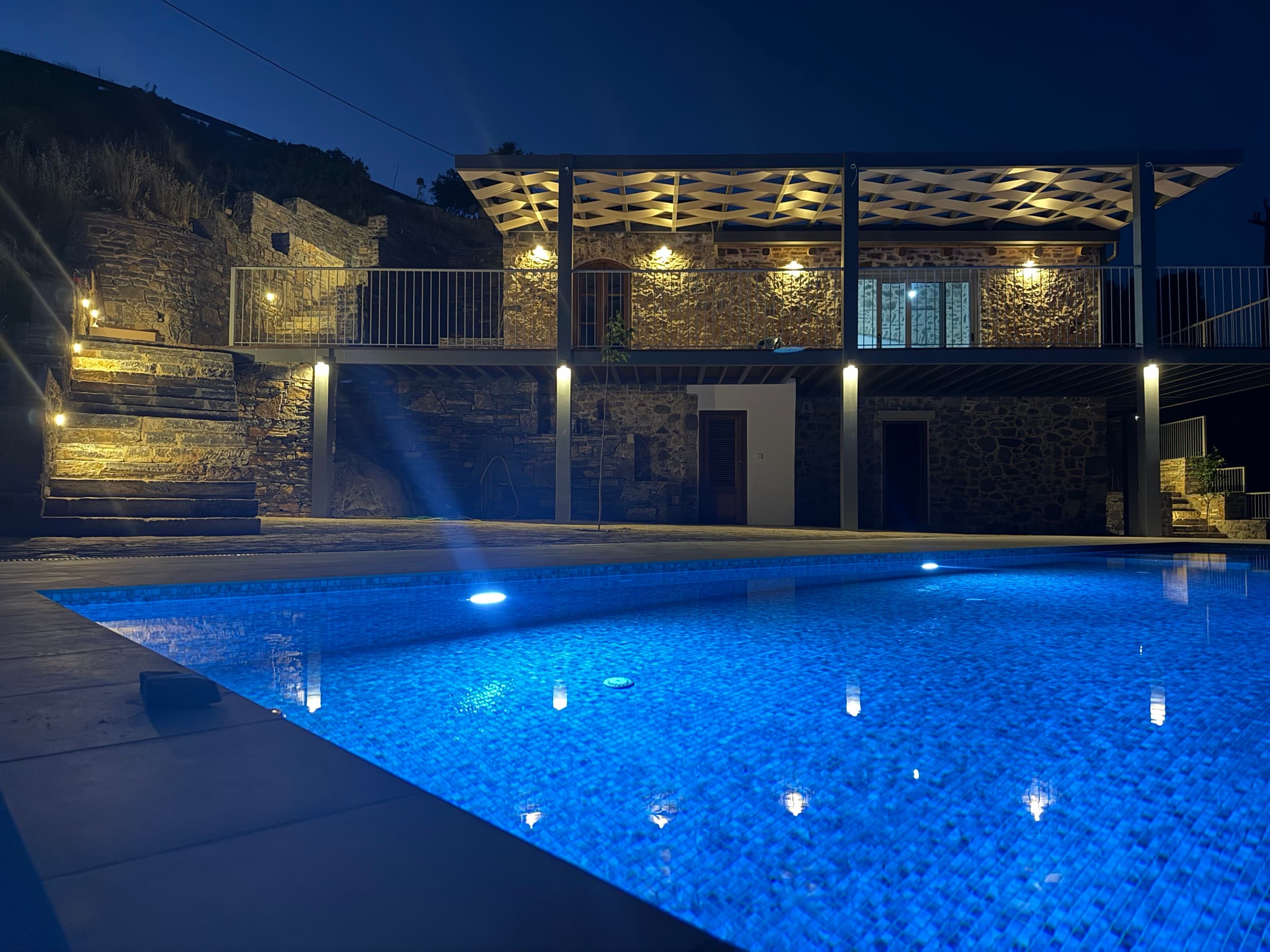 The Stone House at night, stone facade and infinity pool illuminated