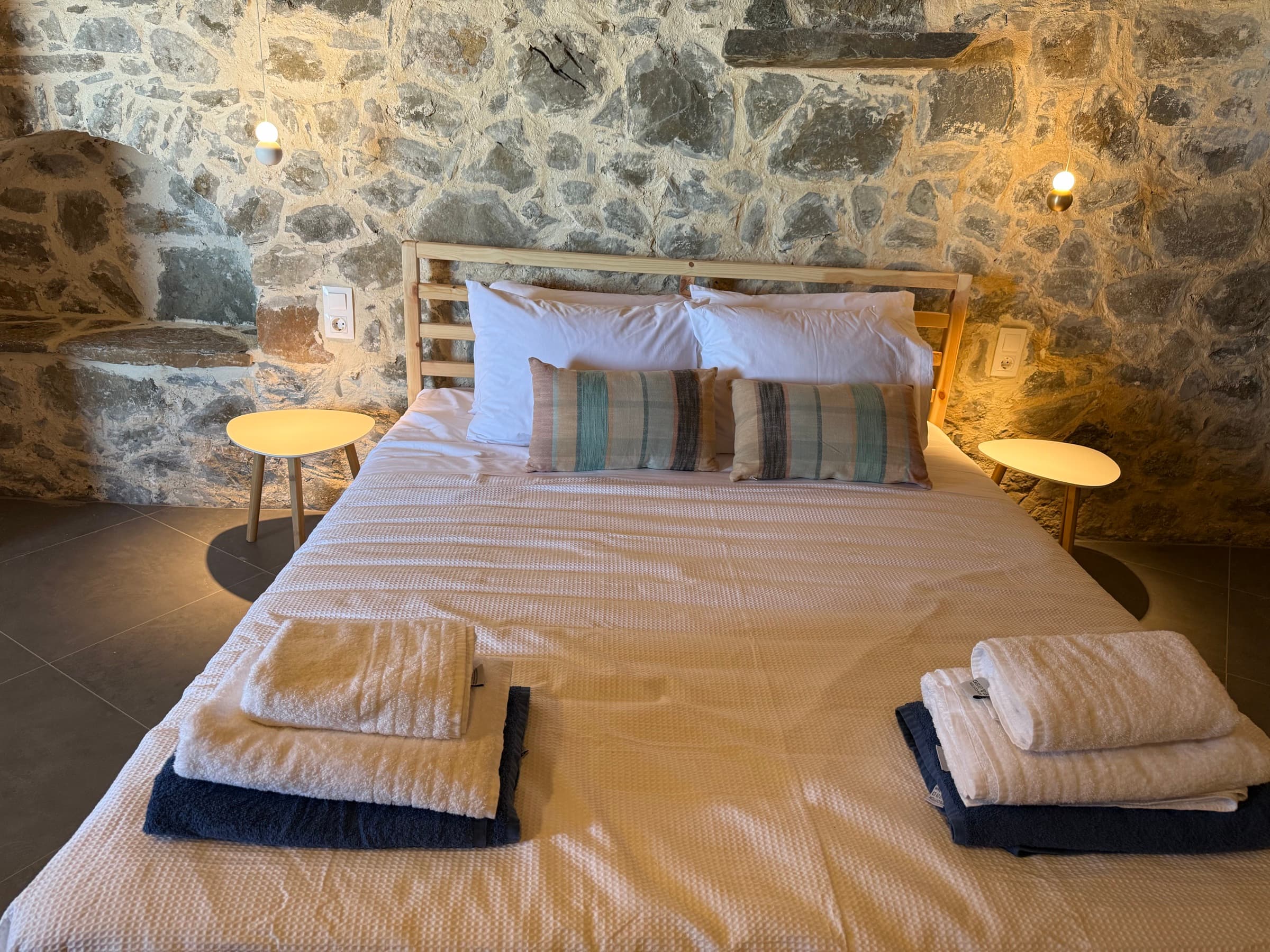 Jasmine suite at pool level — double bed against the stone wall, pendant lights