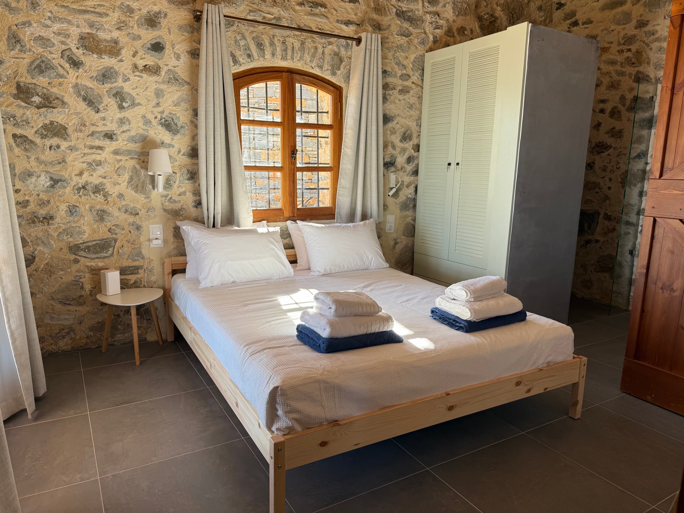 Sea Breeze suite — wide bed beneath the window, stone walls