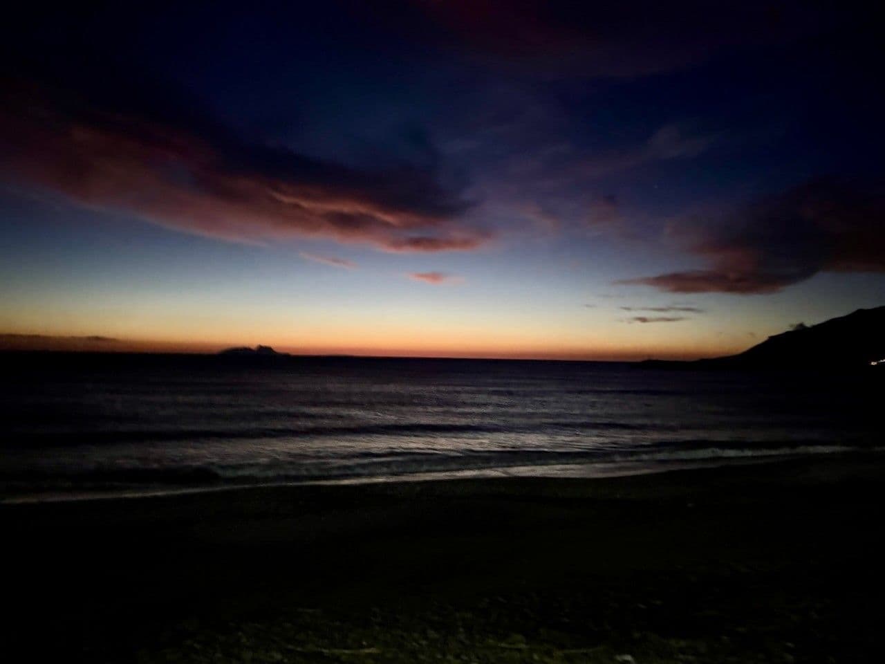 The Paximadia islands as a silhouette at dusk, orange sky over a dark sea