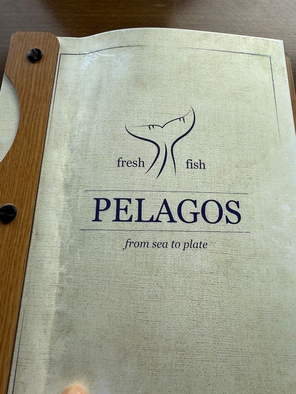 The Pelagos menu cover: a fish tail and the words fresh fish, from sea to plate