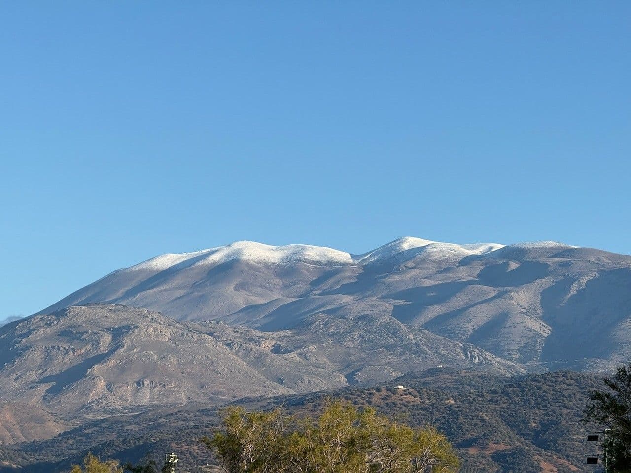 The snow-covered ridge of Psiloritis under a clear blue sky, seen from the hills above the house
